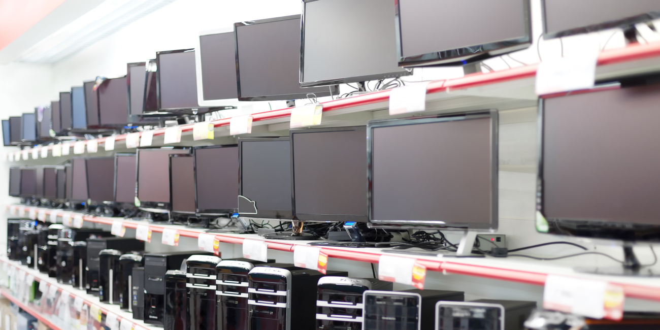 A wide range of desktop computers and monitors displayed on shelves in a tech shop, showcasing the variety offered by reliable computer suppliers in South Africa.